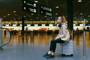 Mulher de máscara esperando voo em aeroporto