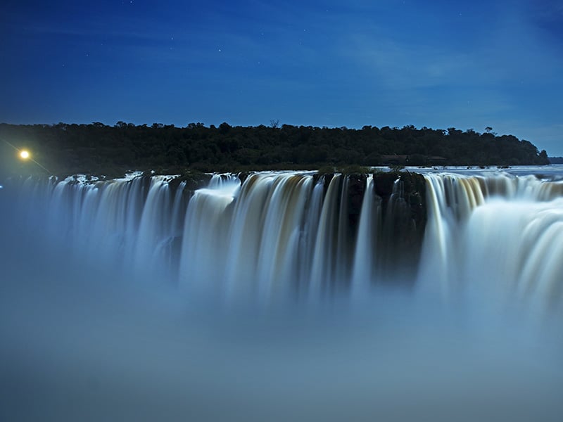 A foto mostra as cataratas do Iguaçu ao anoitecer.