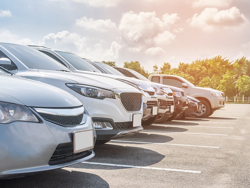 A foto mostra várias faixas de estacionamento com carros estacionados.