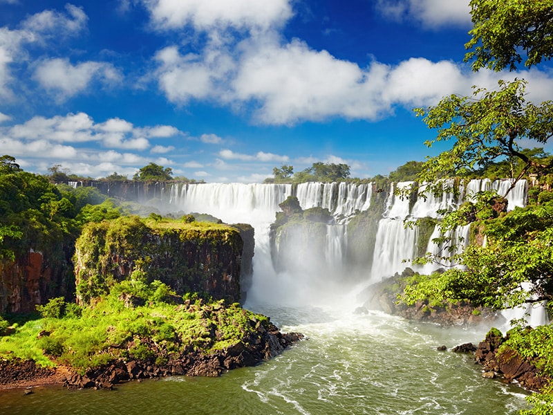 As imponentes cataratas do Iguaçu em um cenário deslumbrante misturado de cores verdes e azul.