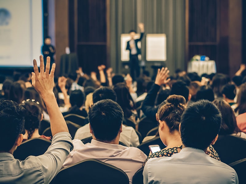 A foto mostra um público durante uma palestra.