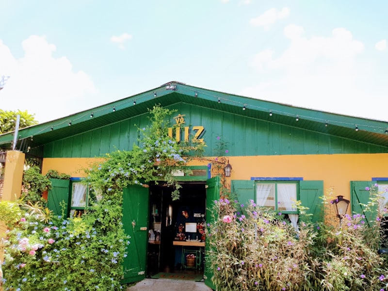 A foto mostra a fachada pintada de verde e amarelo do Vô Luiz Pizzeria e Cucina.